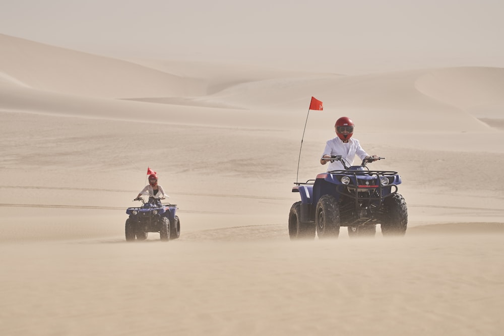 two people riding four wheelers in the desert