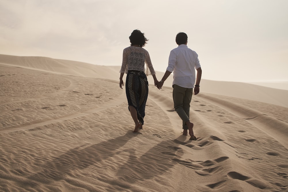 Un uomo e una donna che camminano nella sabbia tenendosi per mano