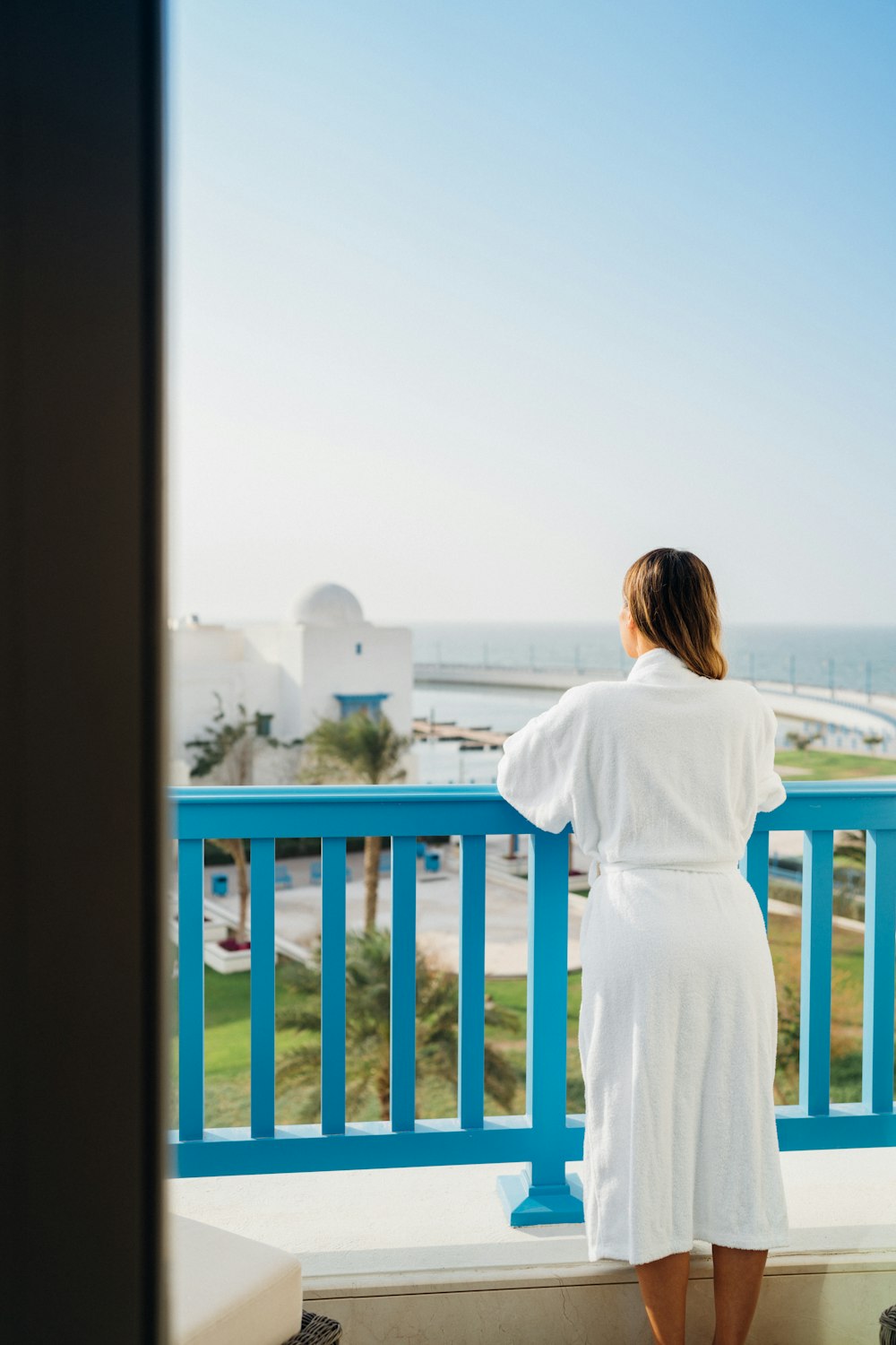 a woman standing on a balcony looking out at the ocean