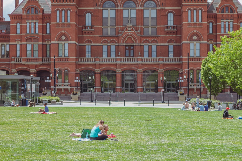 a group of people sitting on top of a lush green field