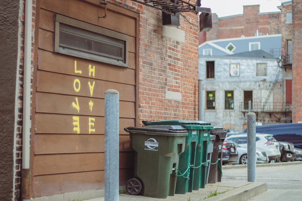 a row of trash cans sitting on the side of a building