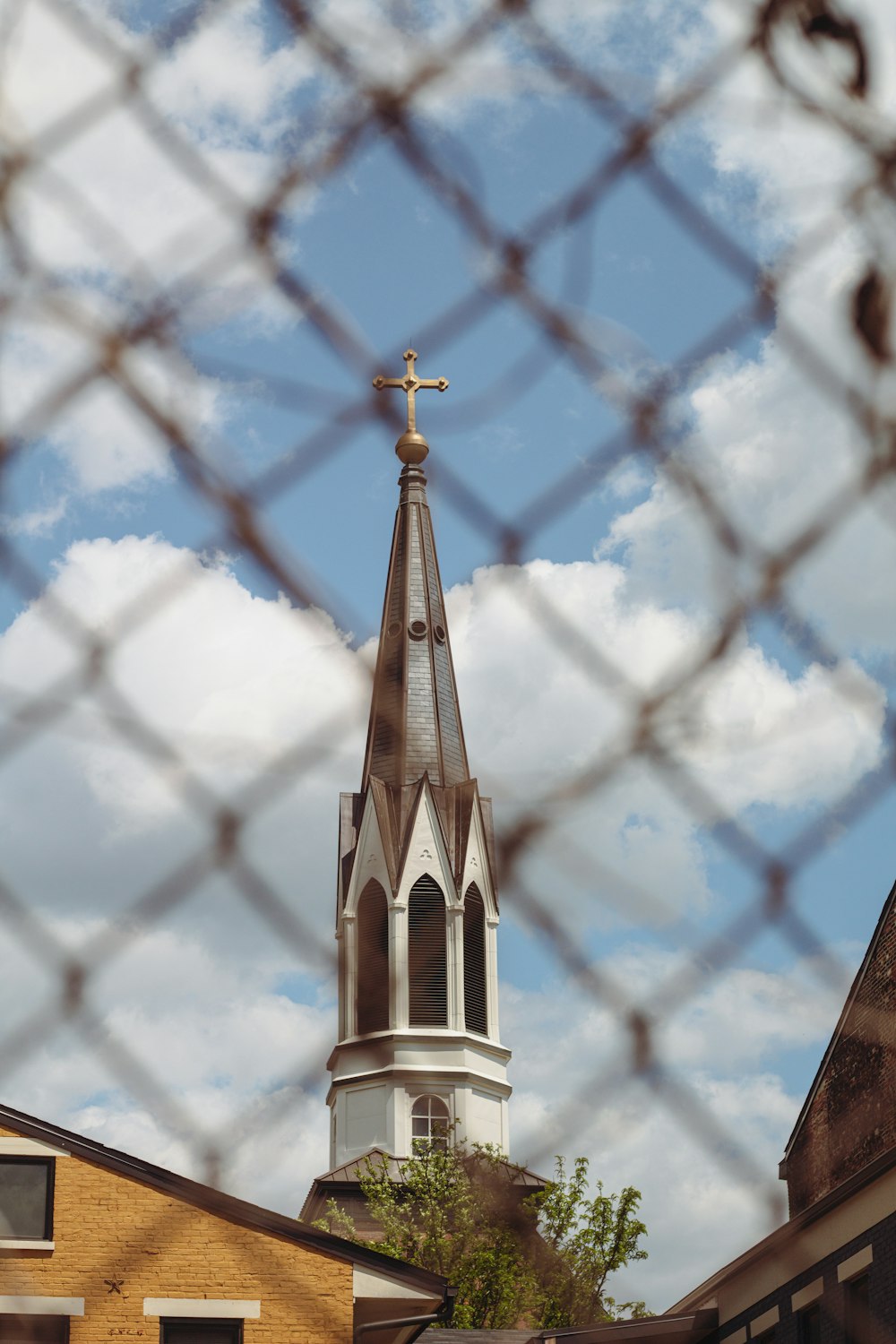 a church steeple seen through a chain link fence