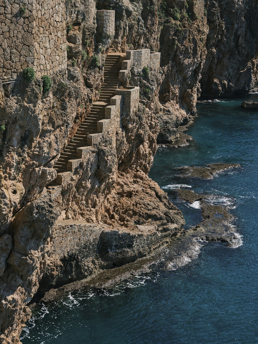 a rocky cliff next to a body of water