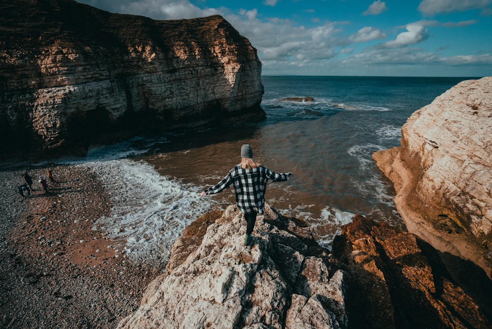 a man standing on top of a rock next to the ocean