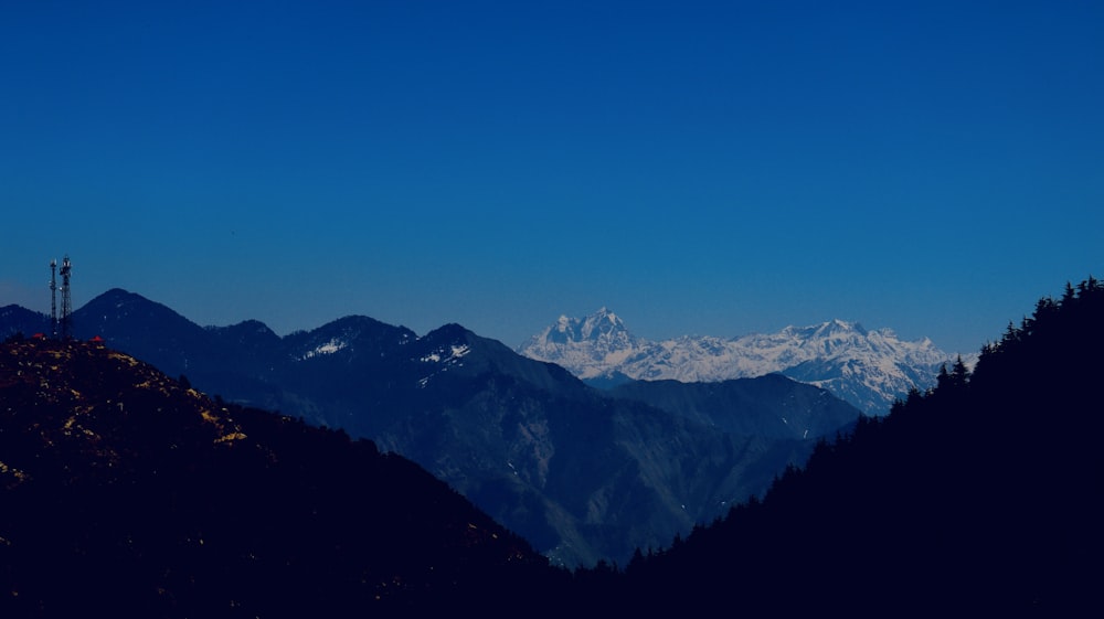 a view of a mountain range with a radio tower in the foreground