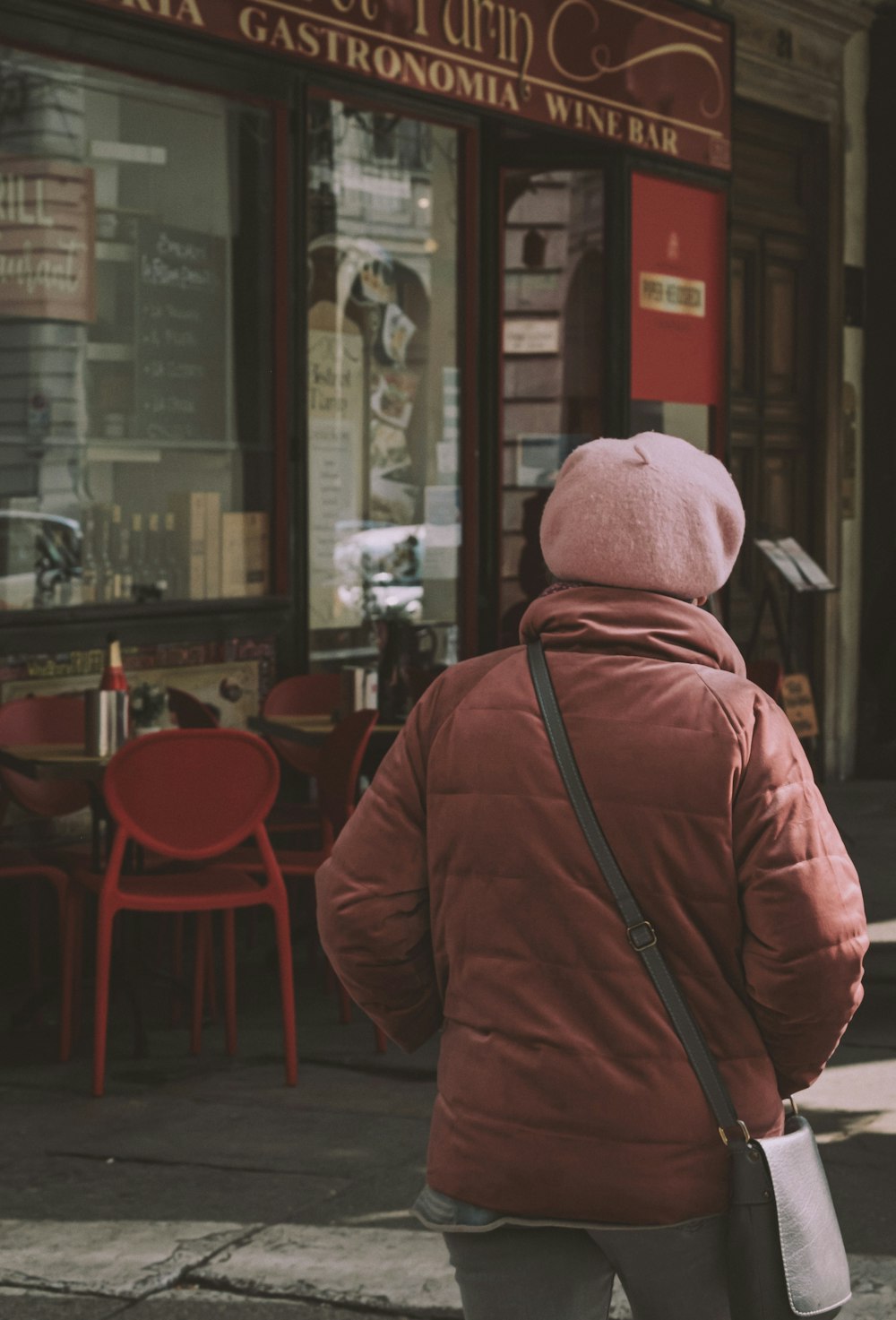 uma mulher andando por uma rua passando por um restaurante