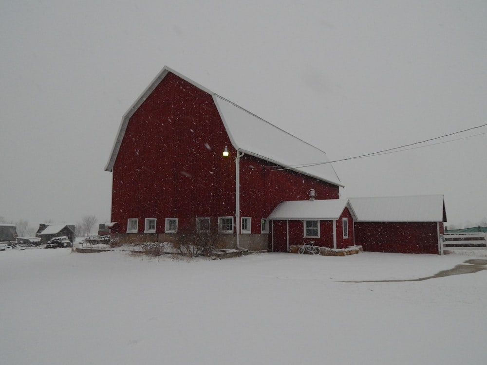 a red barn in the middle of a snowy field