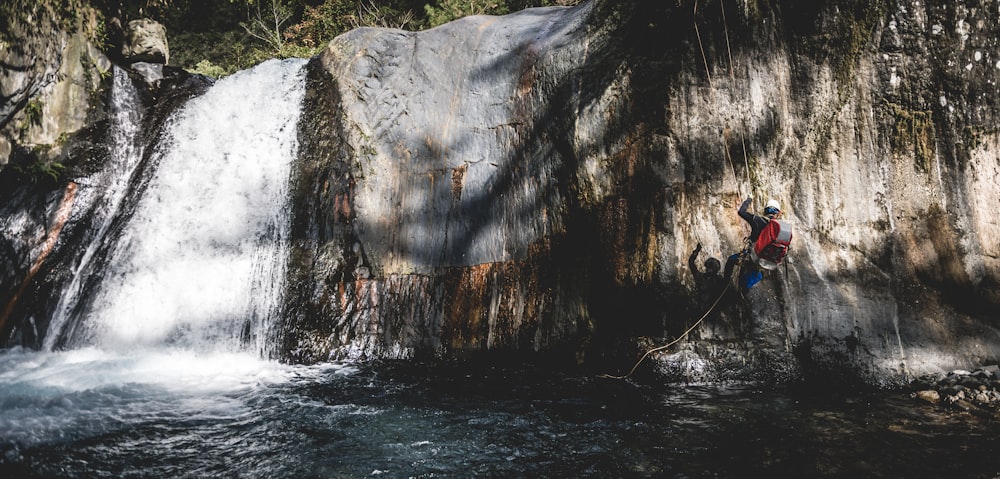 a man standing on a rock next to a waterfall