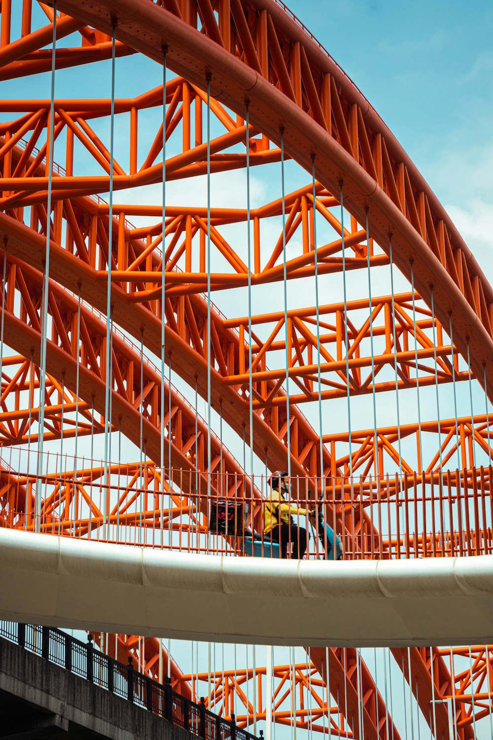 a man standing on a bridge with an orange structure in the background