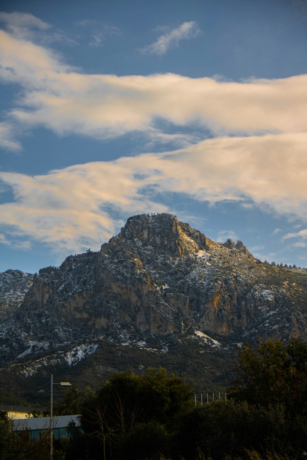 a mountain with snow on it and some clouds in the sky