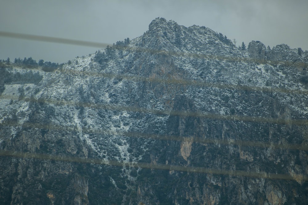 a mountain covered in snow behind a wire fence