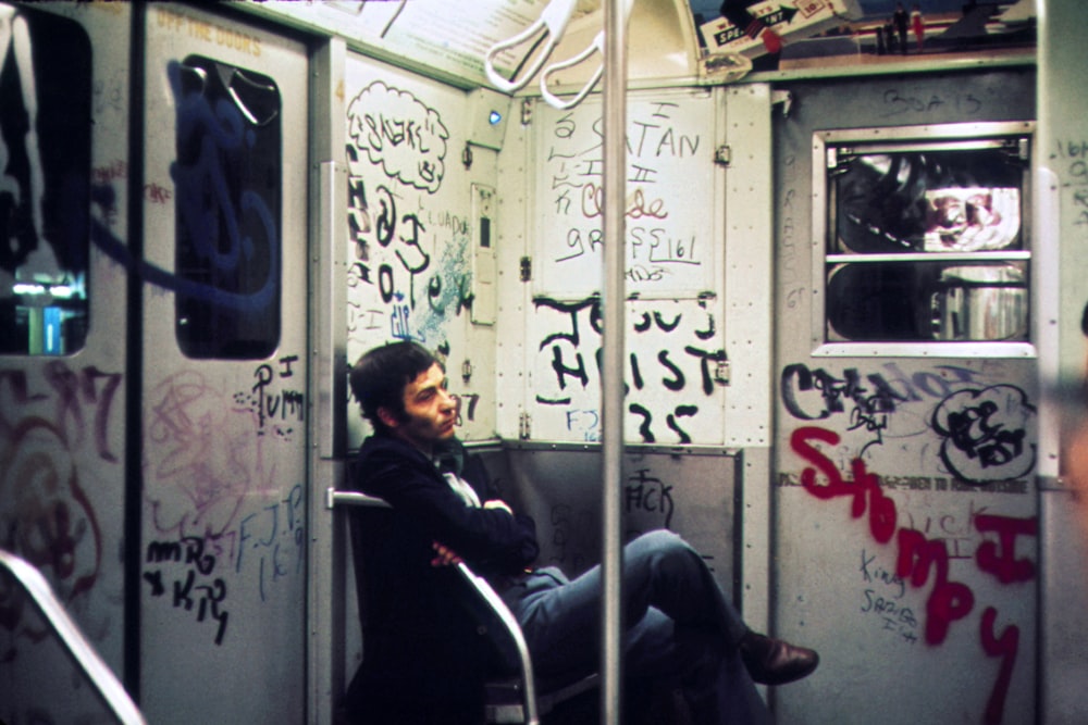 a man sitting on a subway car covered in graffiti