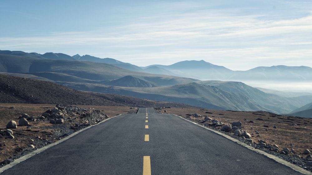 an empty road with mountains in the background