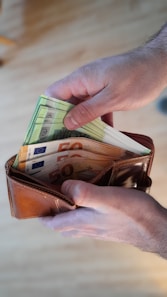 a person is holding a wallet full of money
