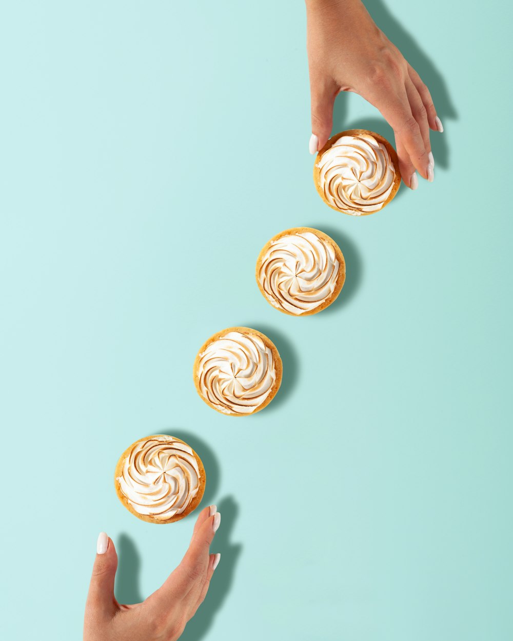 a woman's hands reaching for a pastry on a blue background
