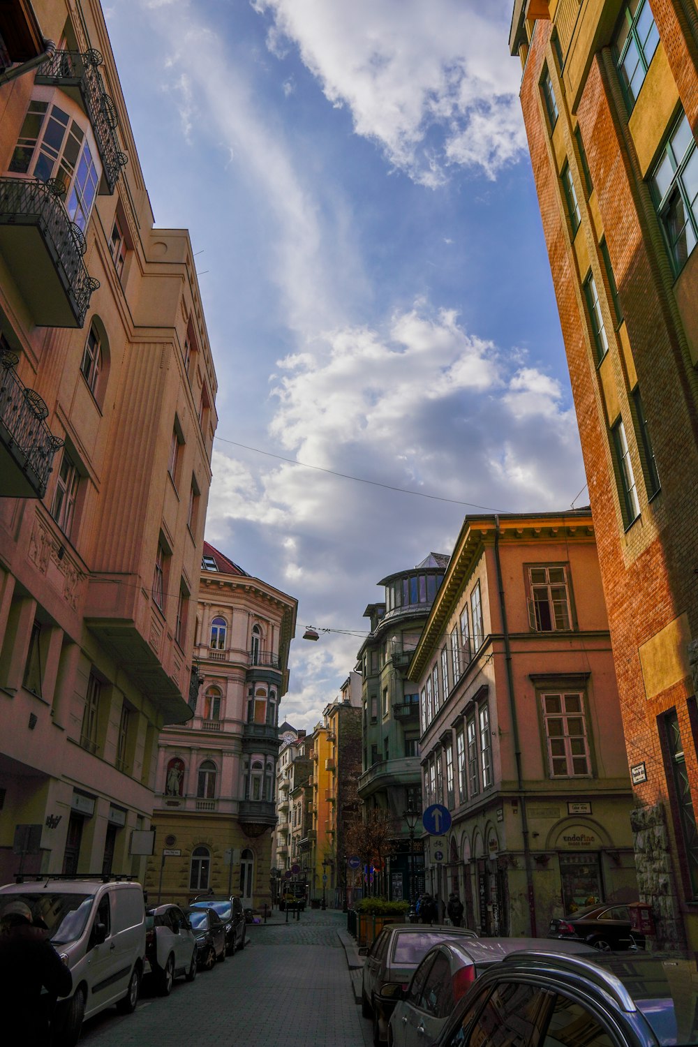 a city street lined with tall buildings under a cloudy blue sky