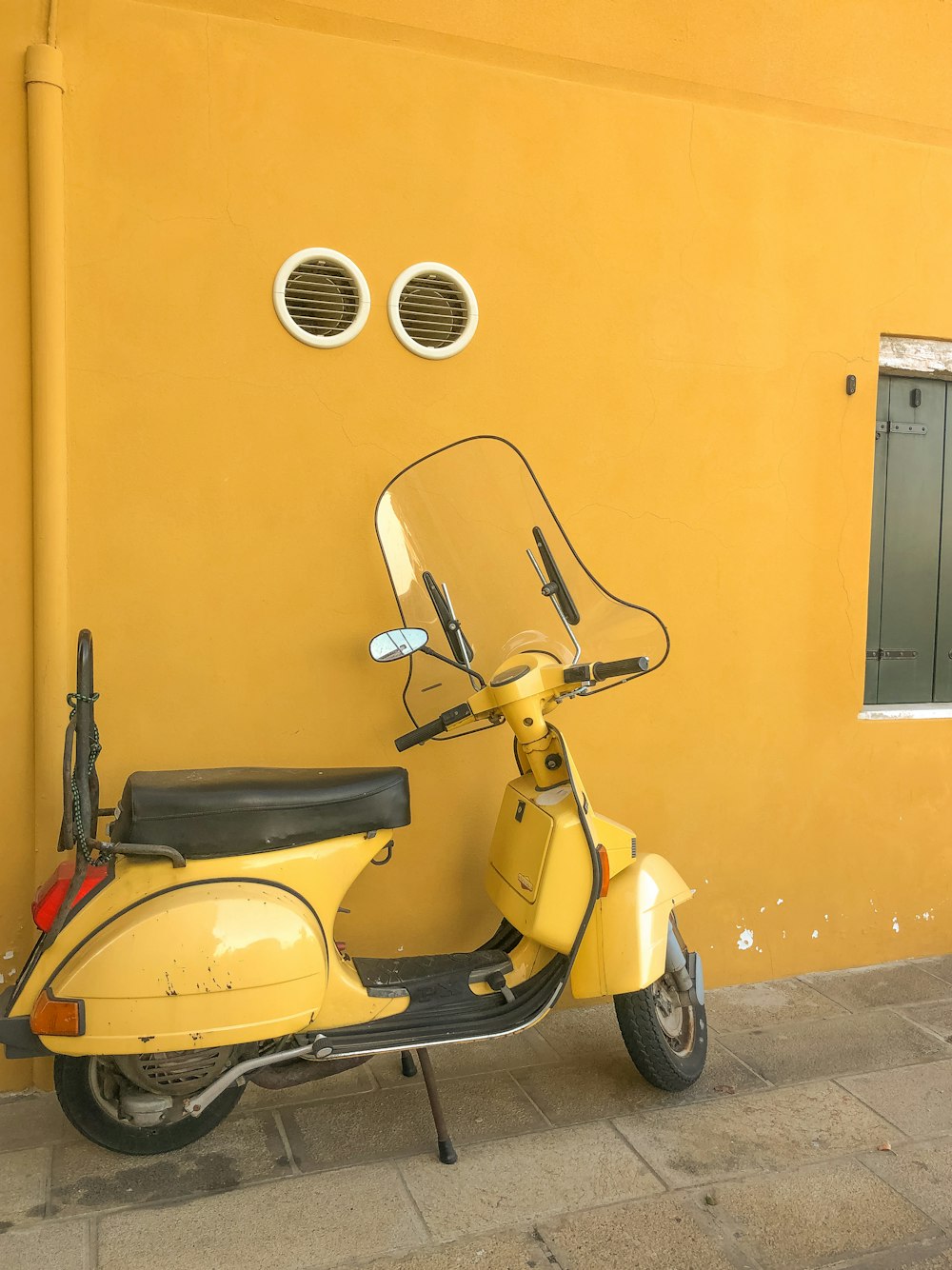 a yellow scooter parked next to a yellow building