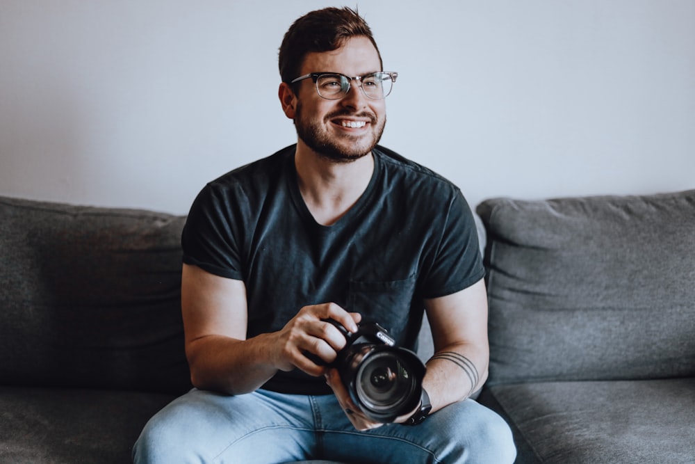 a man sitting on a couch holding a camera