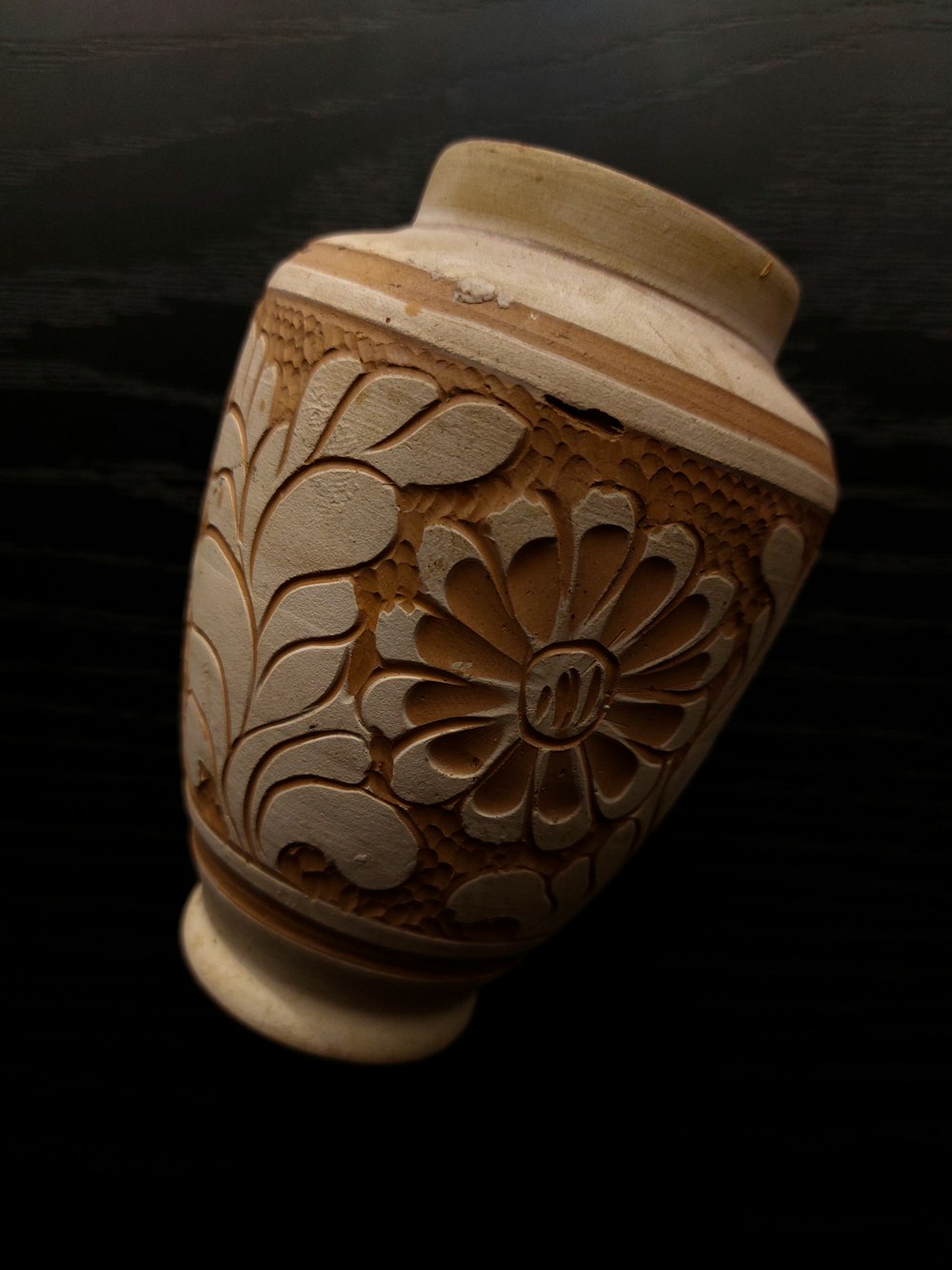 a brown vase with a flower design on it