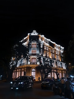 a building lit up at night with cars parked in front of it