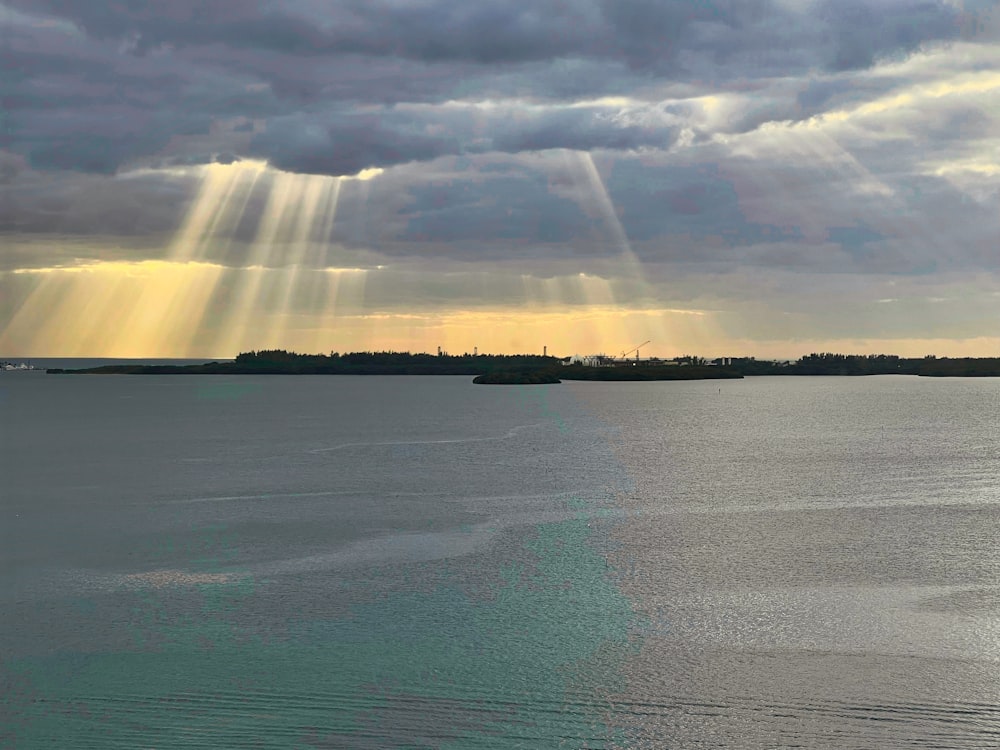 the sun shines through the clouds over a body of water