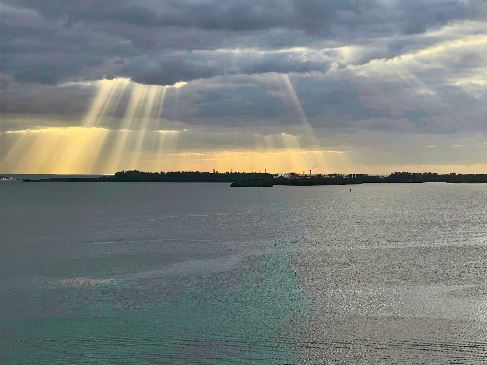 sun shining through clouds over water