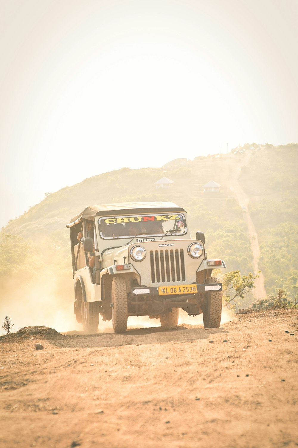 Un jeep conduciendo por un camino de tierra cerca de una colina