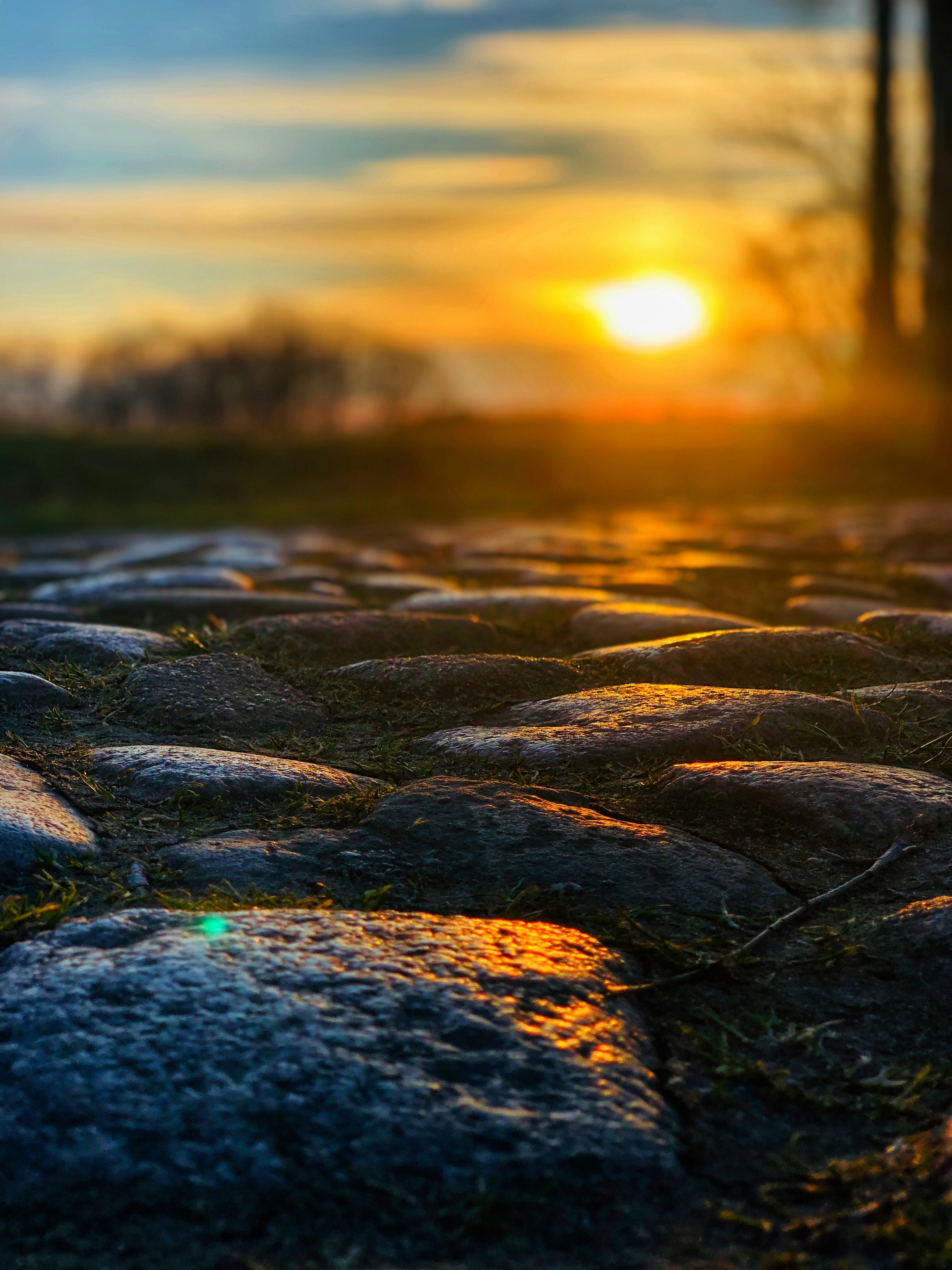 the sun is setting over a cobblestone road