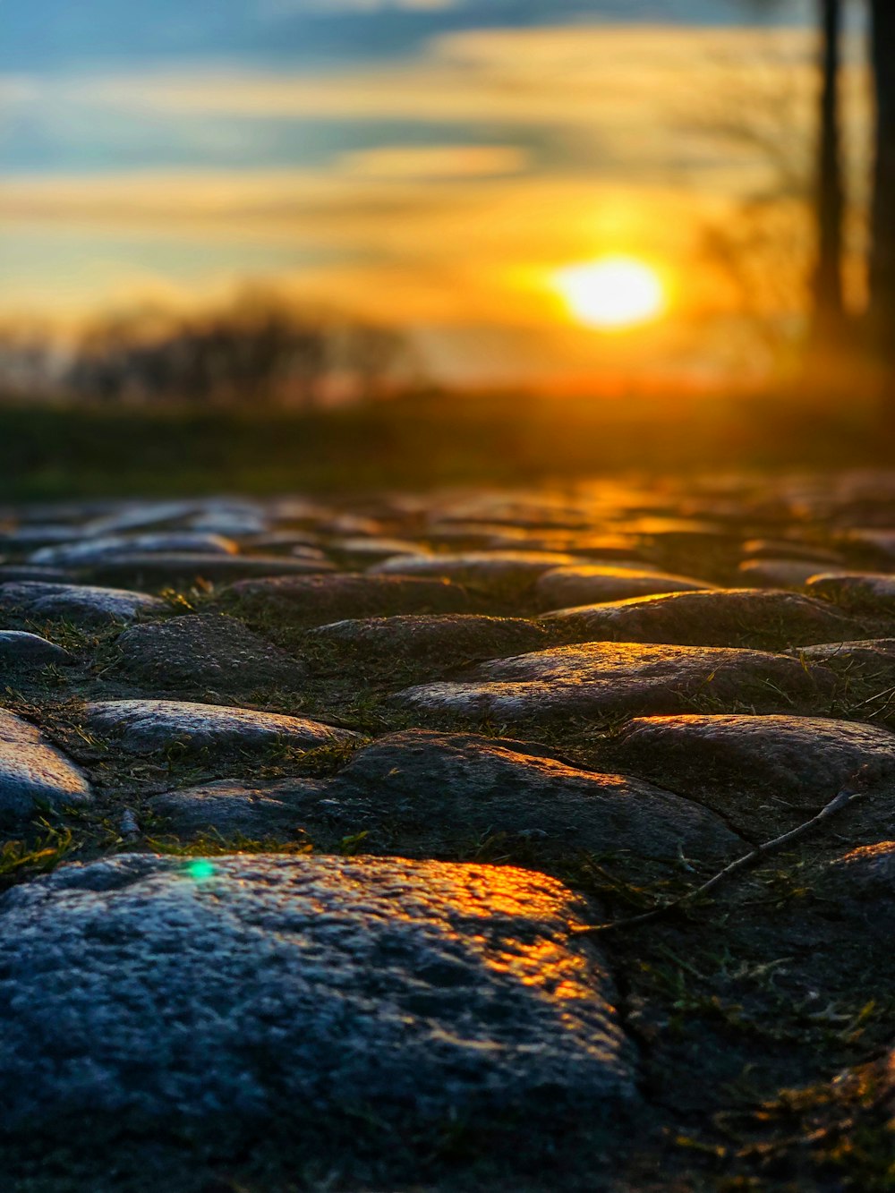 the sun is setting over a cobblestone road