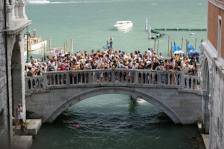 a crowd of people standing on a bridge over a body of water