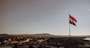 a flag flying high in the sky over a city