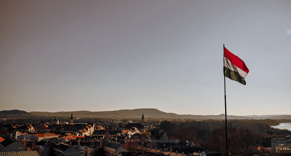 a flag flying high in the sky over a city