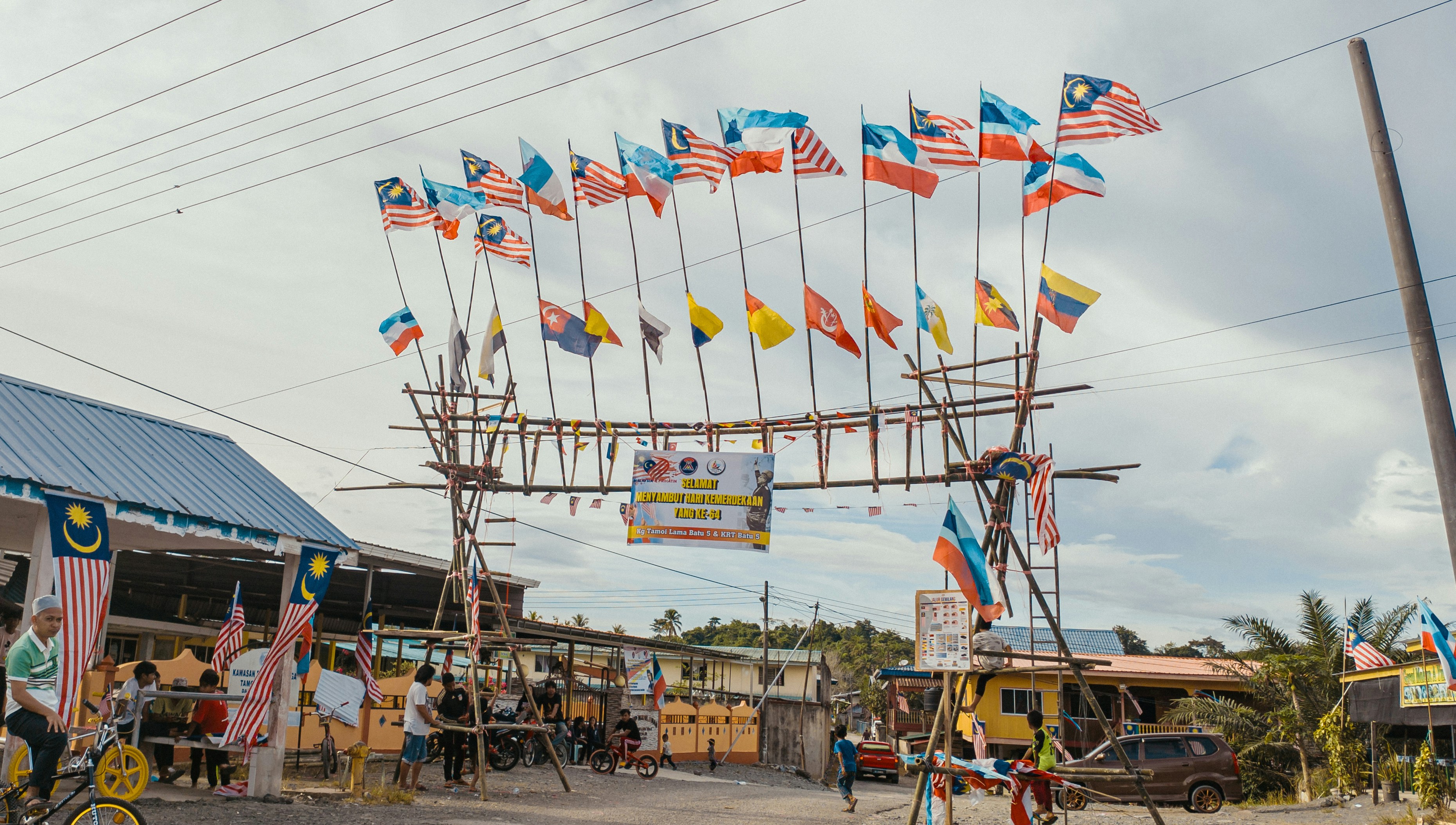 a group of people standing under a wooden structure with flags on it