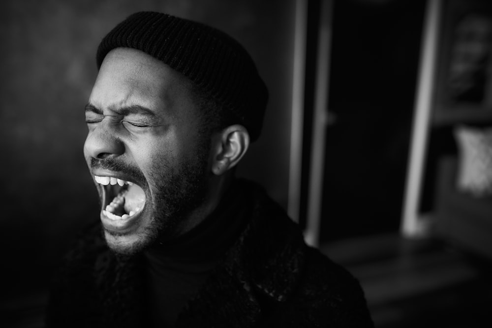 a black and white photo of a man with his mouth open