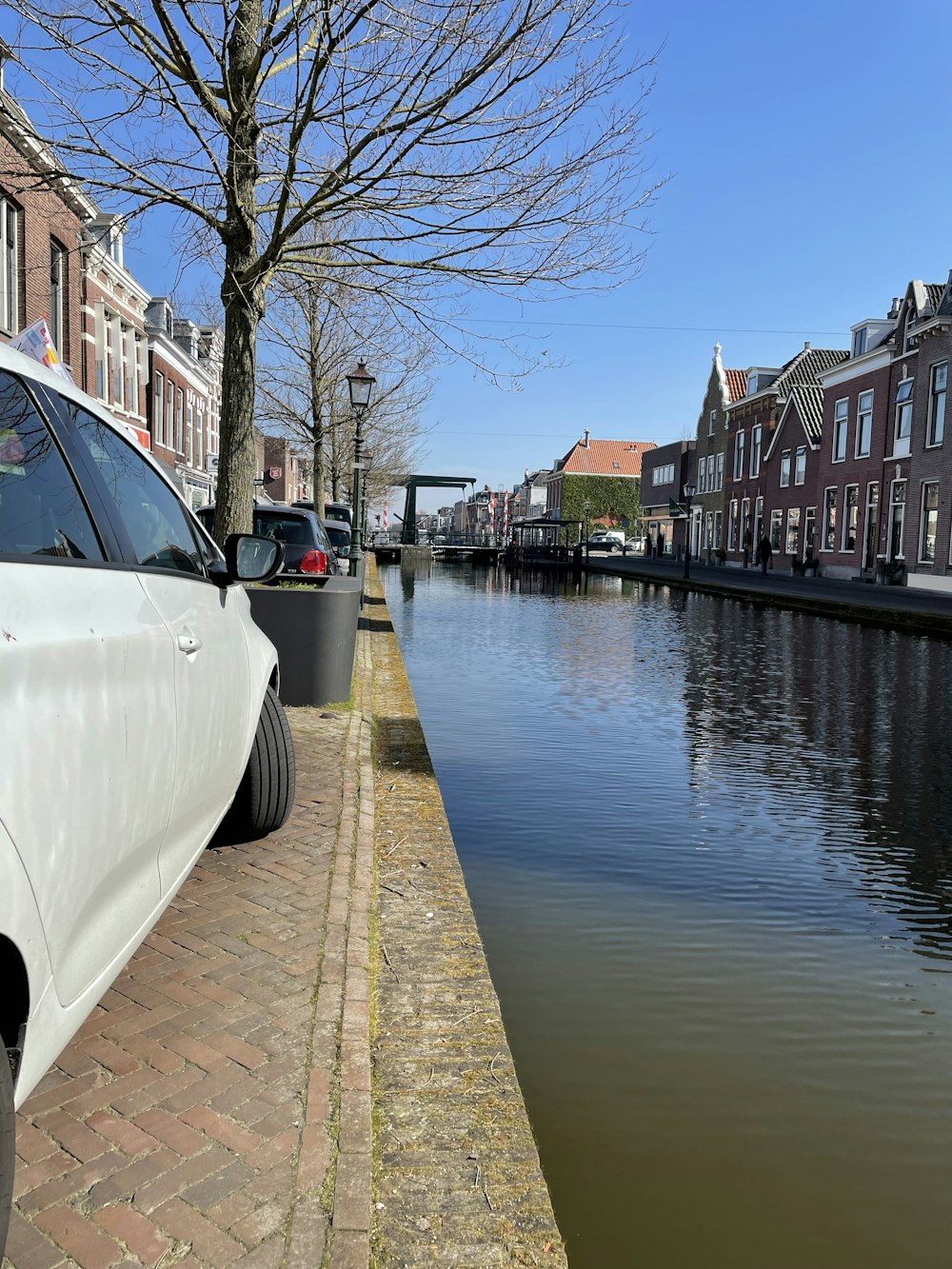 a white car parked on the side of a road next to a body of water