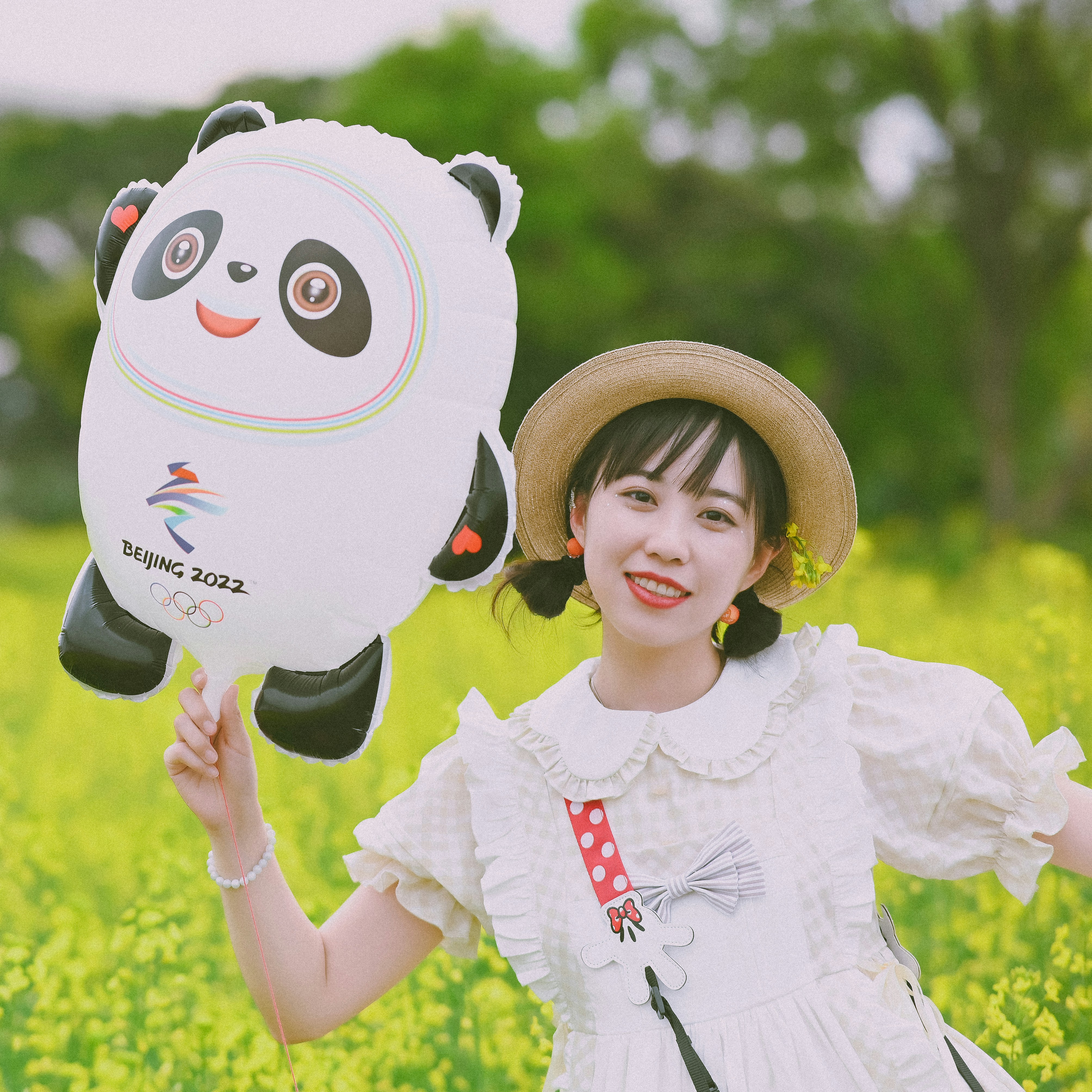 Ein junges Mädchen hält einen Pandaballon auf einem Feld