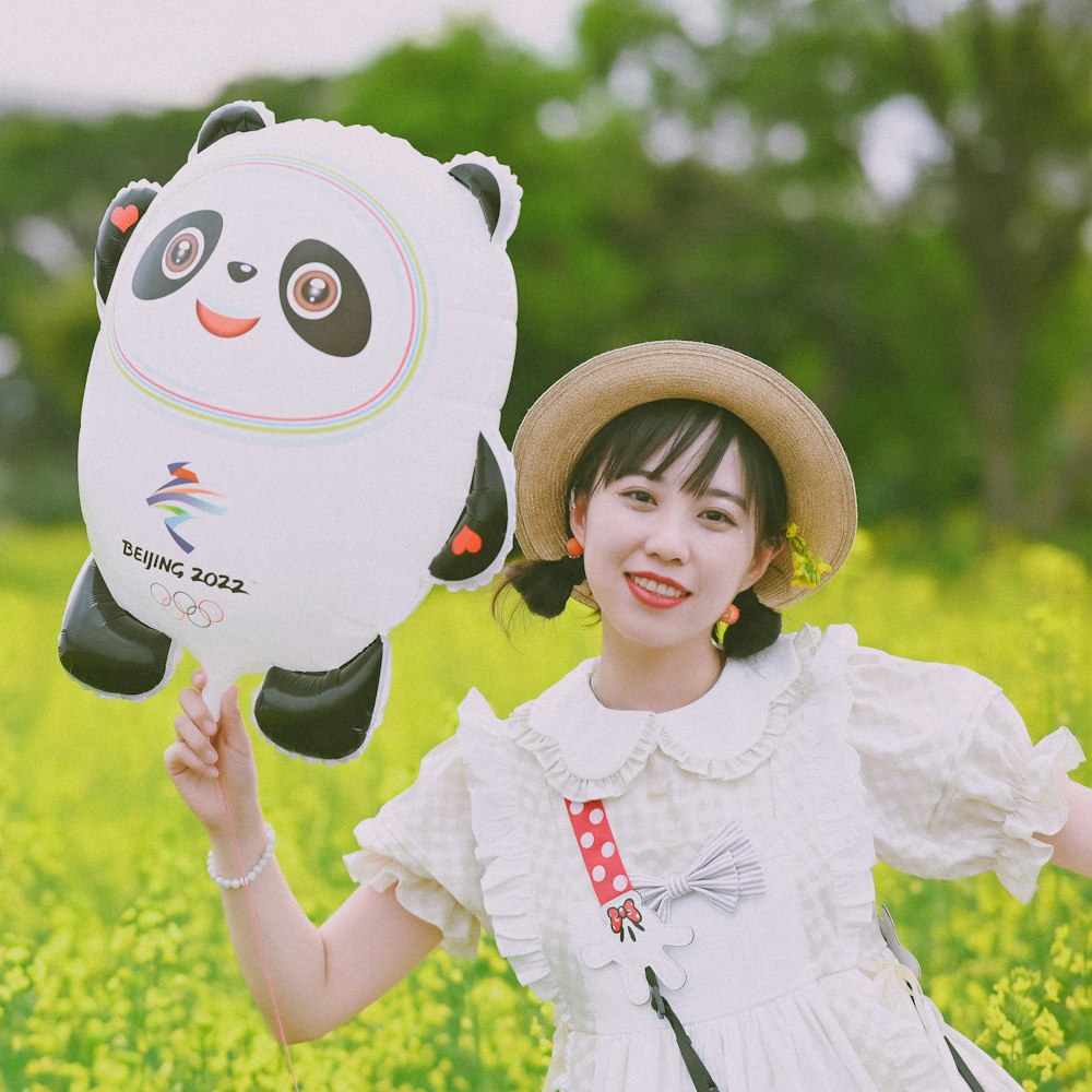 a young girl holding a panda balloon in a field