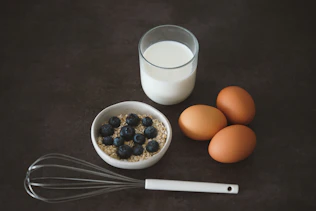 a bowl of oatmeal, eggs, and a glass of milk