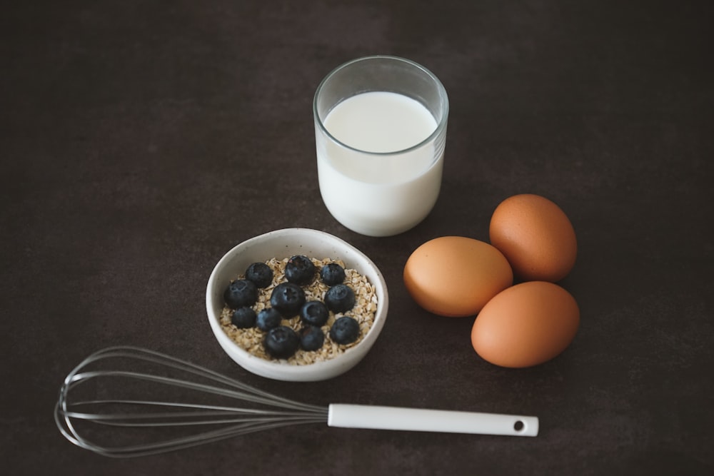 a bowl of oatmeal, eggs, and a glass of milk