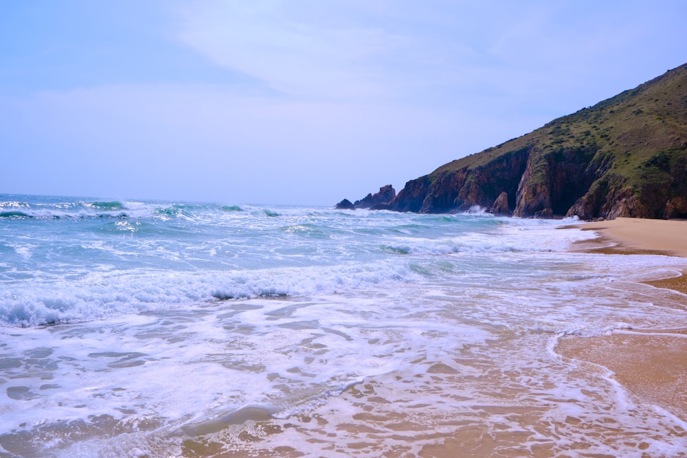 a sandy beach with waves coming in to shore