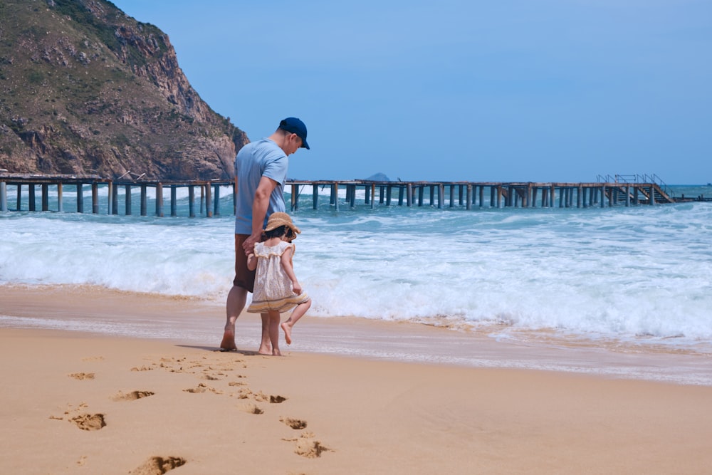 a man and a little girl standing on a beach