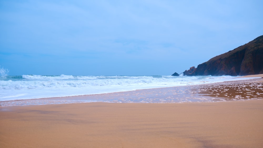 a sandy beach with waves coming in to shore