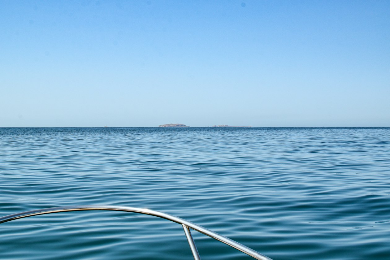 Open Pacific water seen from the bow of a boat on a Marietas Islands tour, with low islands on the horizon