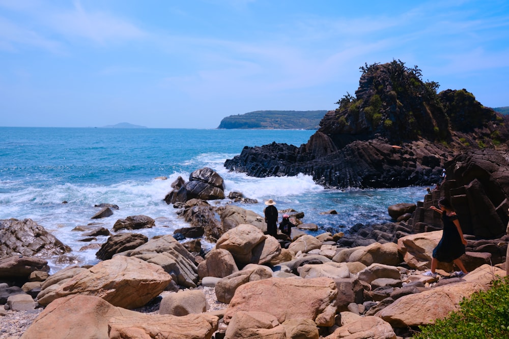 a couple of people standing on top of a rocky beach