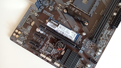 Close-up of computer hardware components including SSD, RAM modules, and a motherboard.
