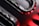 Curved metallic and glossy elements intertwine with smooth, reflective surfaces, displaying a sleek, high-tech appearance. The image incorporates sharp contrasts between dark and light sections, with striking red accents providing a bold visual impact.