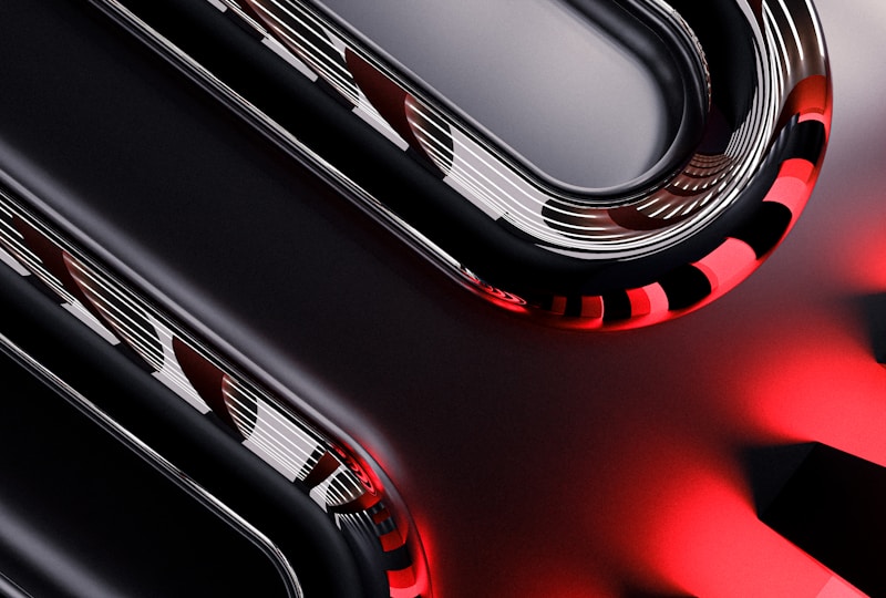 Curved metallic and glossy elements intertwine with smooth, reflective surfaces, displaying a sleek, high-tech appearance. The image incorporates sharp contrasts between dark and light sections, with striking red accents providing a bold visual impact.