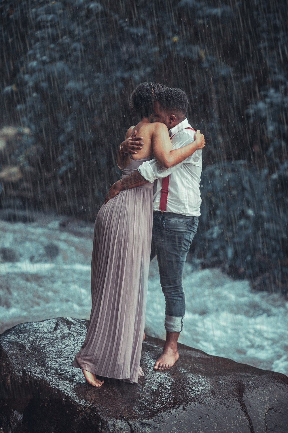 a man and a woman standing on a rock in the rain