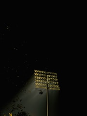 A high mast light illuminating a large outdoor area at night.