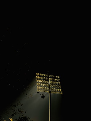 Outdoor warehouse area glowing with durable floodlights on tall poles during dusk.